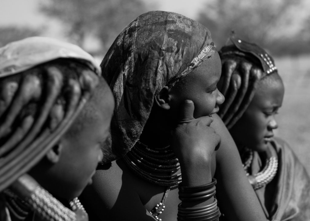 A close-up black and white photo of Himba women adorned in traditional jewelry, a cultural encounter to experience when deciding what to visit in Namibia.