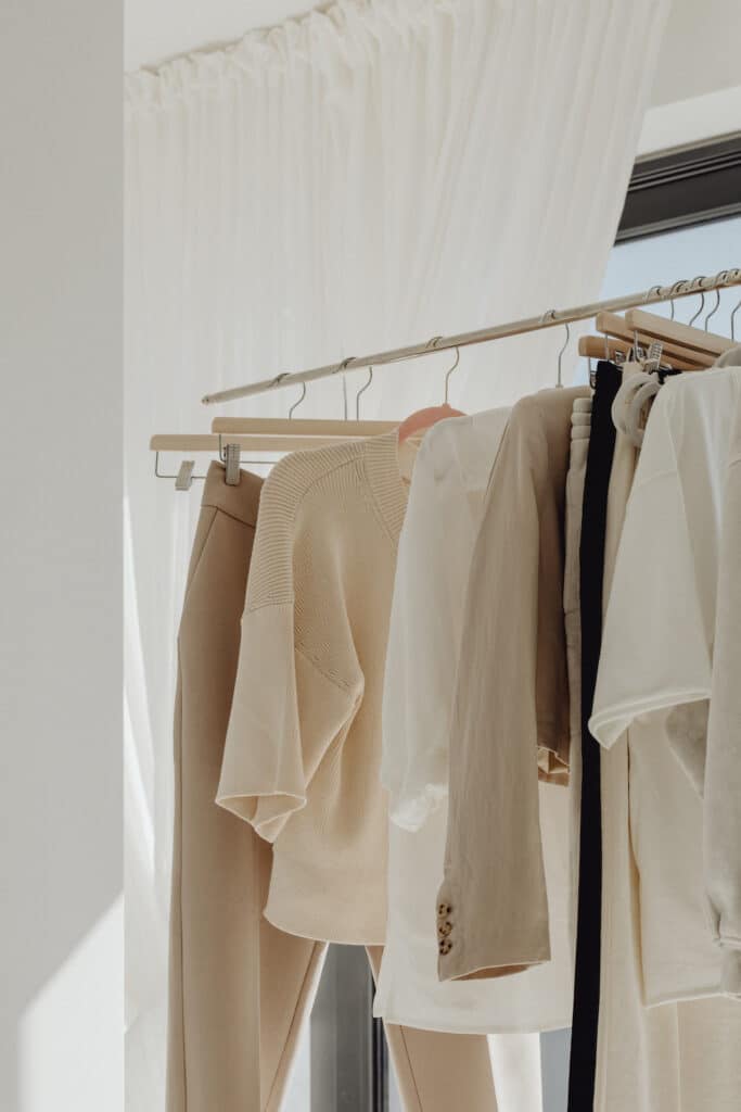 Neutral-toned sustainable garments hanging on a minimalist rack, showcasing the elegance of a sustainable capsule wardrobe.