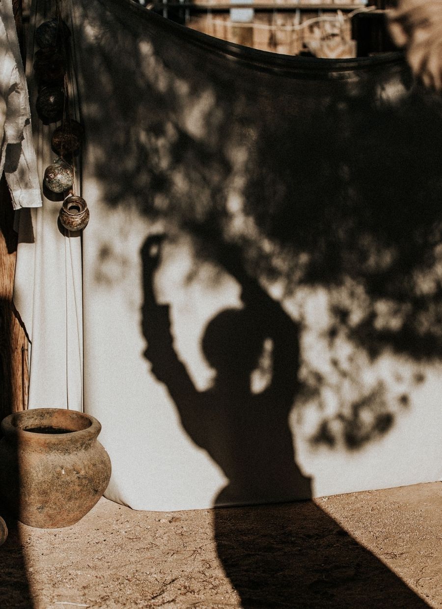 Shadow of a woman wearing a dress in front of a rustic Portugese home
