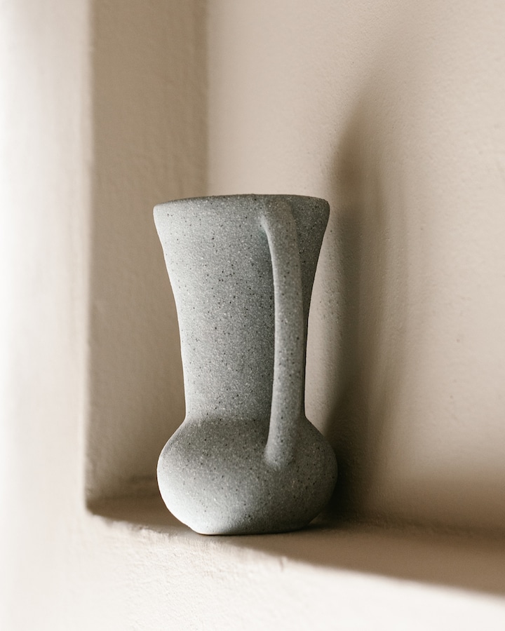  A minimalist ceramic vase rests on a ledge, epitomizing the simplicity and elegance of Kefalonian dining decor.