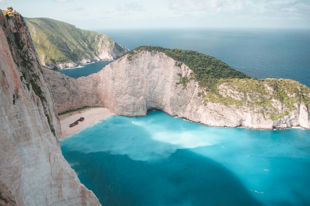 Aerial view of the iconic Navagio Beach, or Shipwreck Beach, in Zakynthos, with its dramatic cliffs and crystal-clear turquoise waters embracing a picturesque stranded ship.