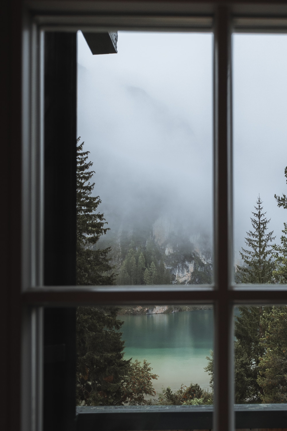 A tranquil lake view from a bedroom window at Hotel Lago di Braies, showcasing the Dolomites' natural splendor which is Lago di Braies, one on the most stunning lakes in the Dolomites.