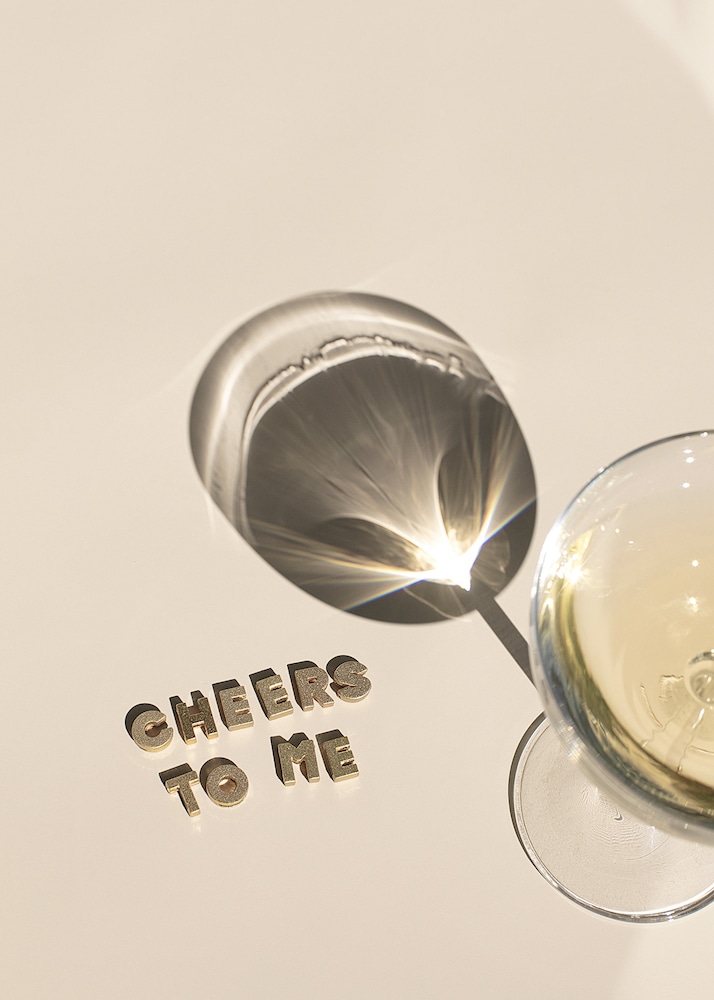 A cocktail shaker pouring a drink into a martini glass with the phrase "CHEERS TO ME" in metallic letters, celebrating personal achievement and self-confidence gained reading Best Confidence Books for low self-esteem