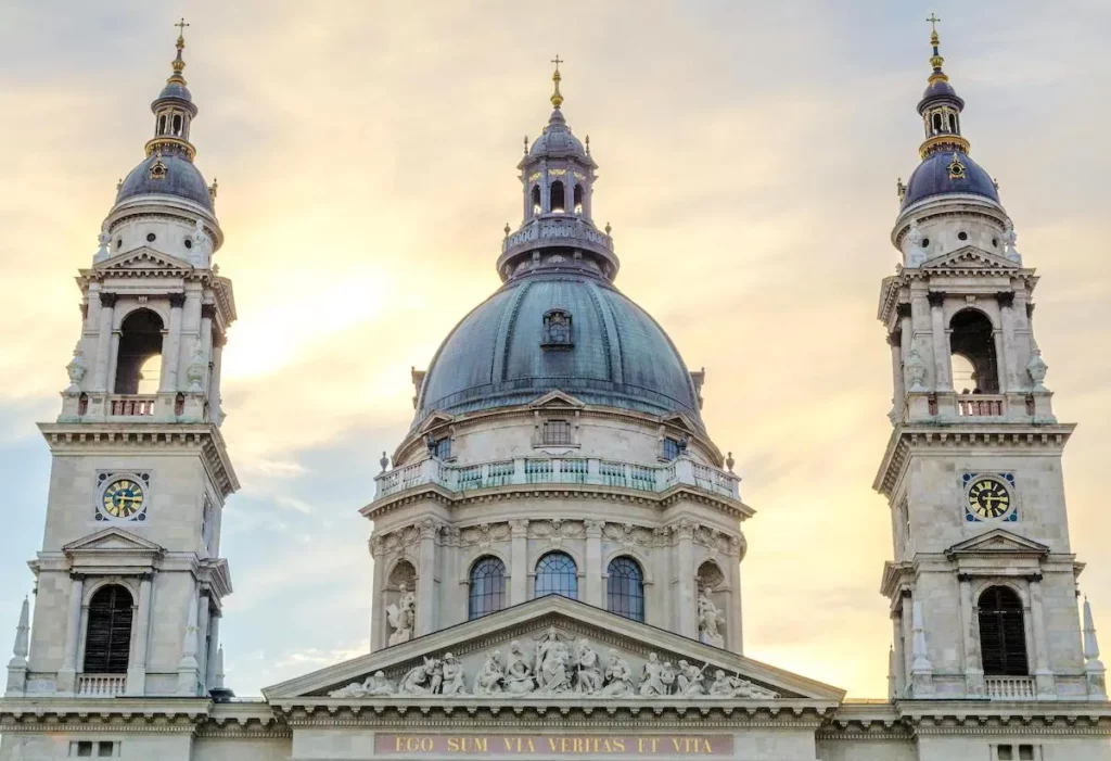 St Stephen's Basilica in Budapest captured in the soft glow of twilight, with its large dome and two bell towers against a pastel sky.