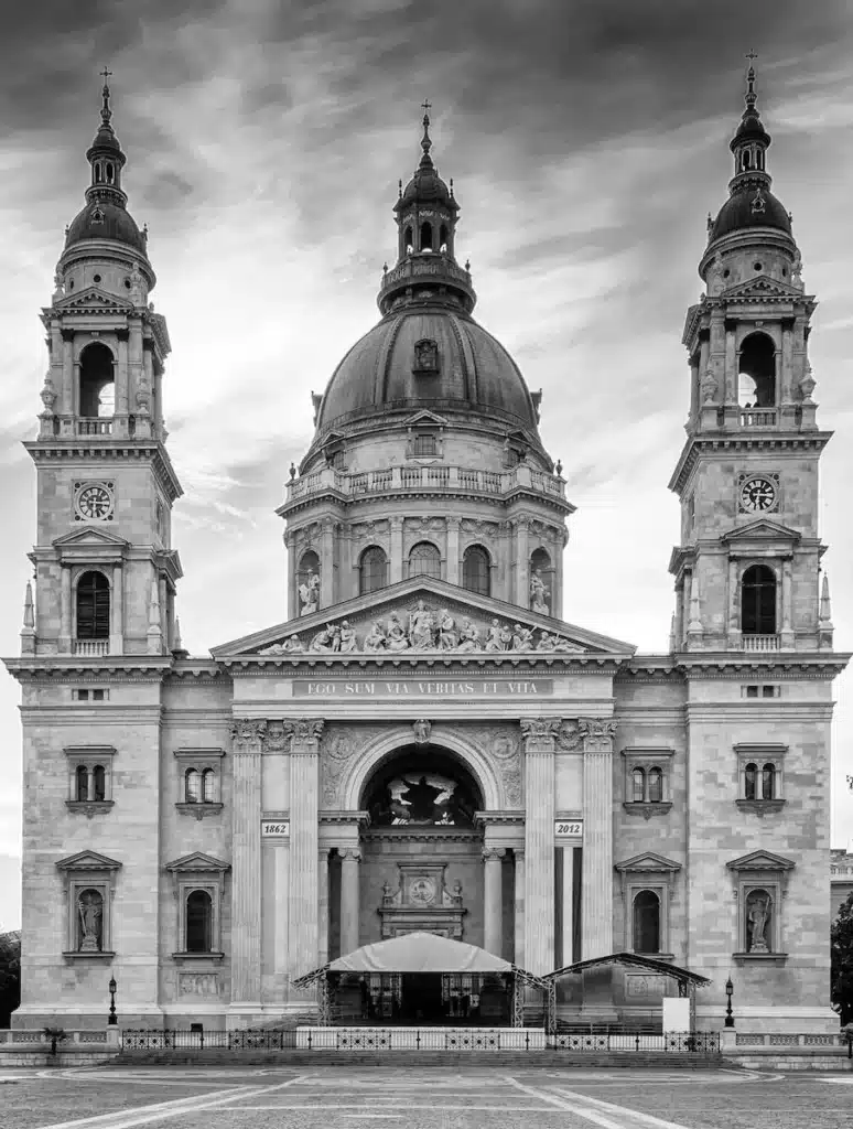 Monochrome image of St. Stephen's Basilica in Budapest, showcasing its detailed façade and twin spires against a dramatic sky."