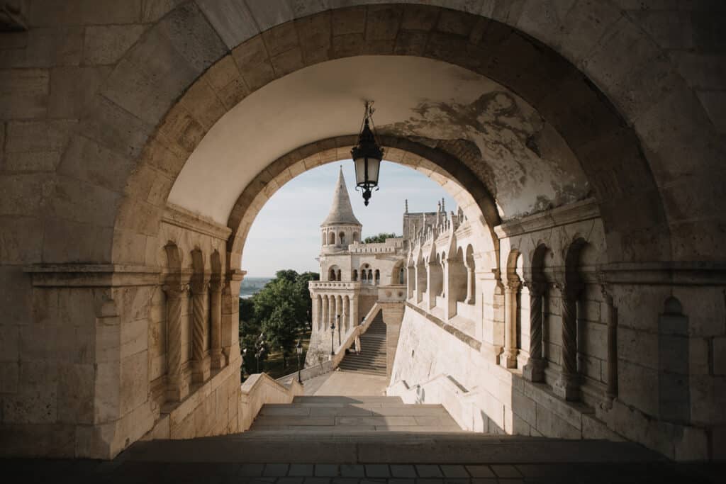 View through an arched passageway at Fisherman's Bastion, with a hanging lantern and stone stairway.