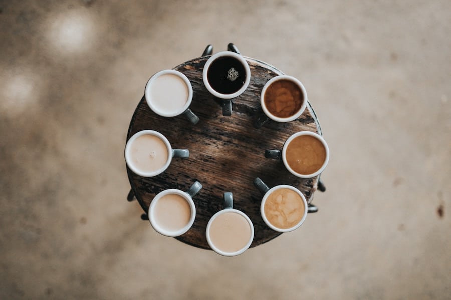 Aerial view of various healthy coffee alternatives arranged in a circular pattern on a rustic wooden table.