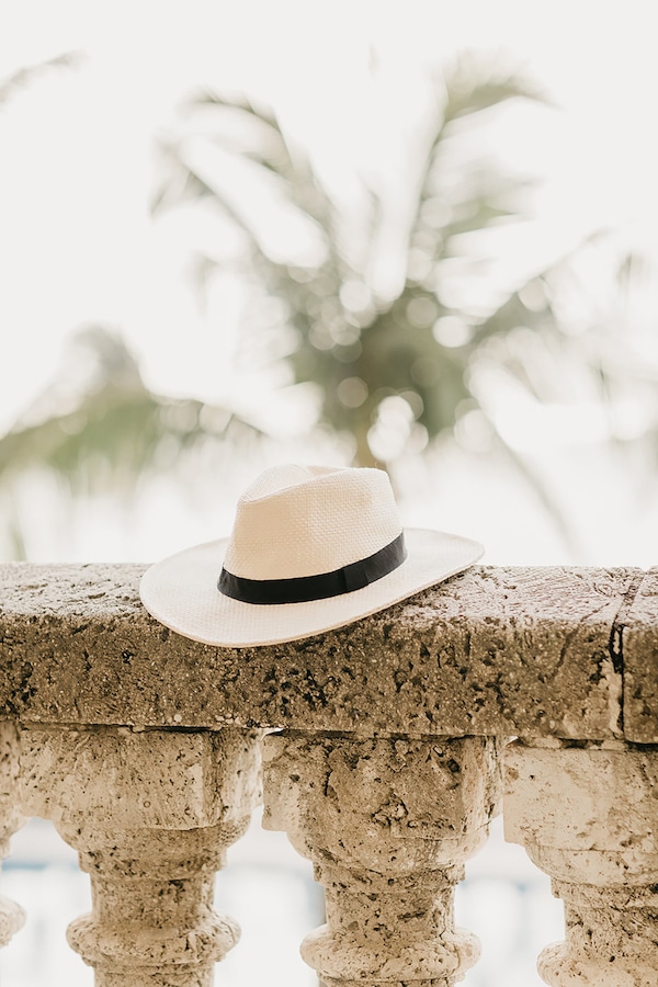Stylish Panama hat resting on an ornate balustrade with a blurred palm tree background, evoking the tropical ambiance of Mauritius and highlighting the importance of where to stay in Mauritius when visiting the island.
