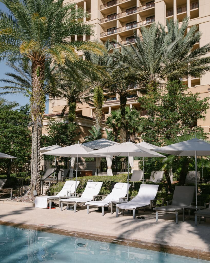 Poolside lounging area with sunbeds and umbrellas at Four Seasons Orlando Disney.