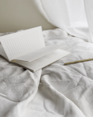 Gif of a book laying on the bed and flipping pages in the wind