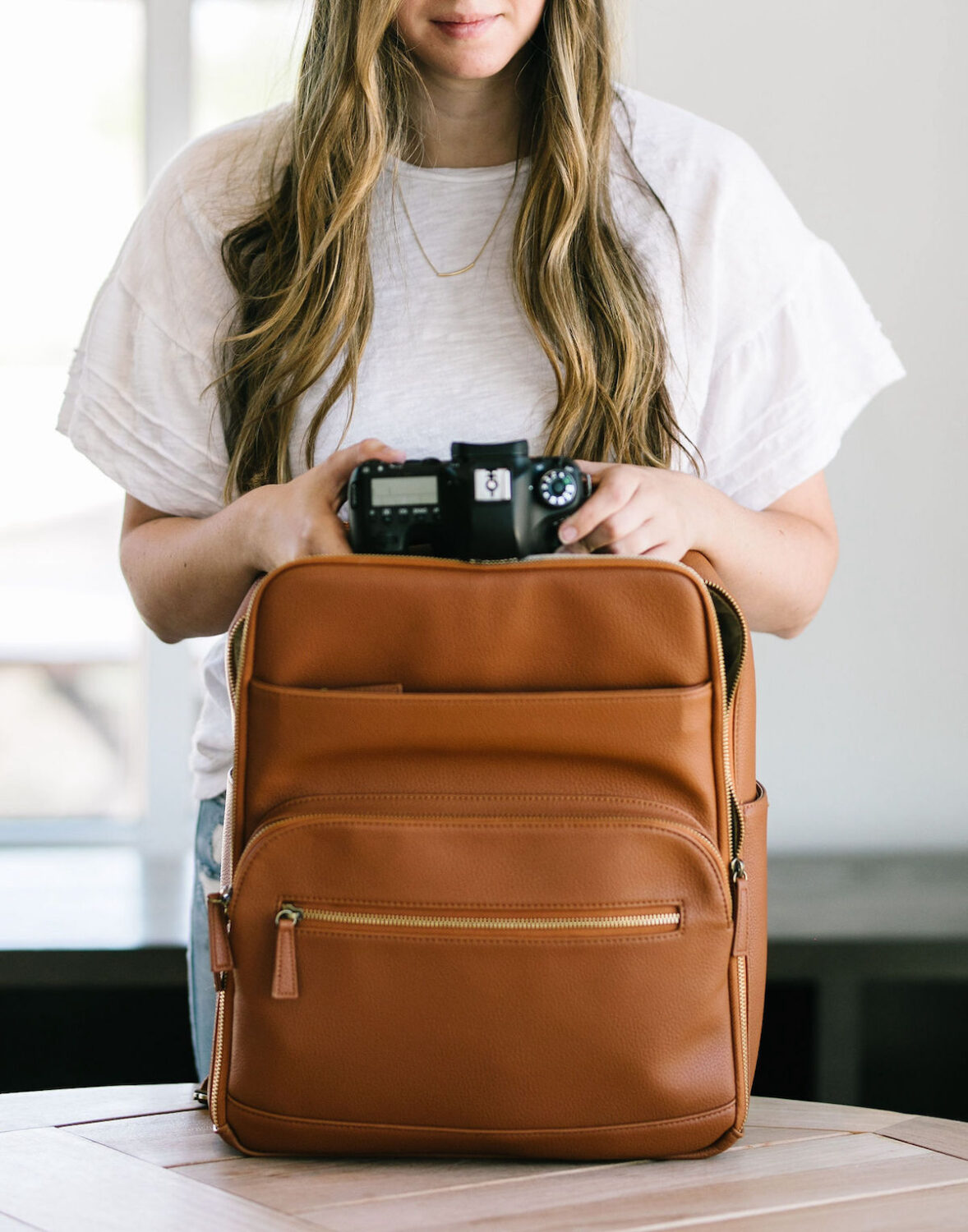 Photographer holding a stylish brown camera backpack from the guide to the best camera bags for Travel