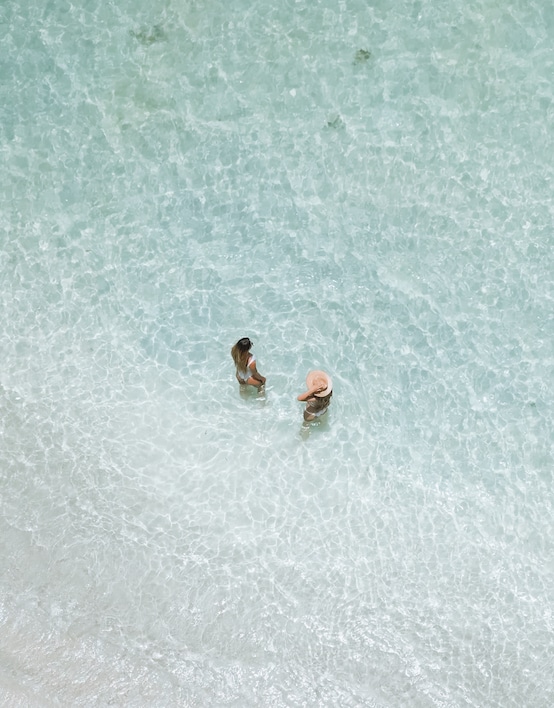 Two people wading in the clear, shallow waters of Ile aux Cerfs, a serene experience