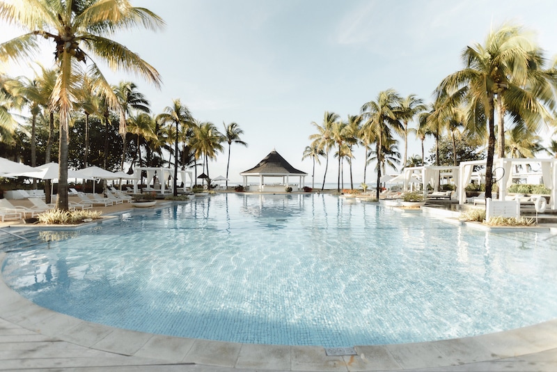 Is Mauritius worth visiting? The tranquil Telfair Heritage Wellness & Spa resort pool in Mauritius, framed by palm trees under a clear sky, beckons travelers exploring if Mauritius is worth visiting