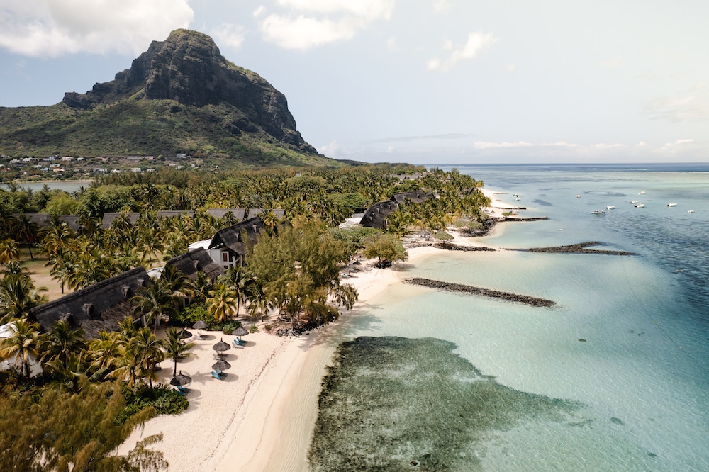Aerial view of the iconic Le Morne Brabant mountain adjacent to a luxury resort on the coast of Mauritius, highlighting the island's dramatic landscapes