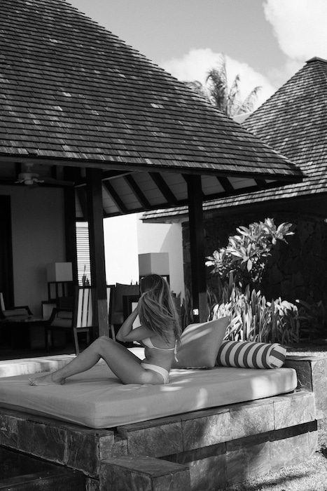 A woman lounges in contemplation at the Four Seasons at Anahita Mauritius, embodying the luxurious tranquility that makes the island worth visiting.