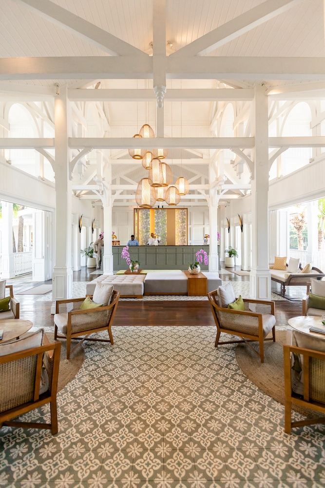 Bright and airy lobby of the Heritage Le Telfair Wellness & Spa Resort in Mauritius, featuring high ceilings, ornate chandeliers, and colonial-style furnishings.