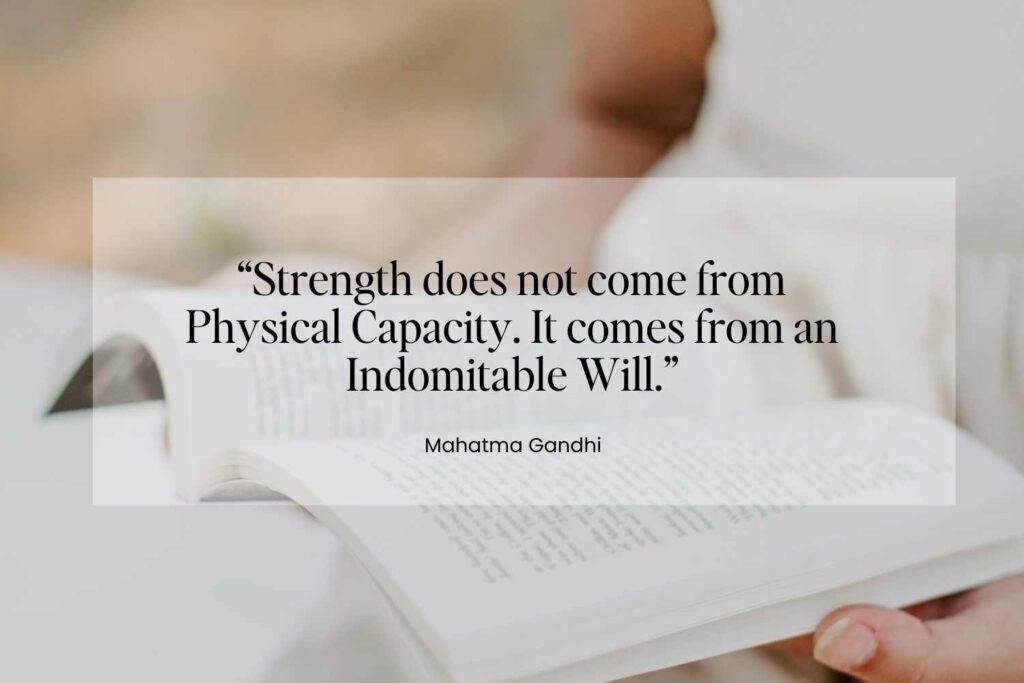 A person holding an open book with a quote by Mahatma Gandhi that reads: 'Strength does not come from physical capacity. It comes from an indomitable will,' exemplifying short spiritual quotes for healing and strength.