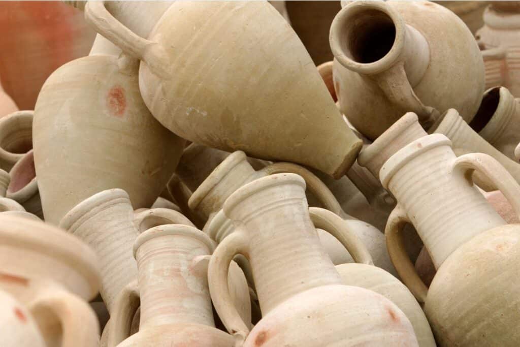 A collection of traditional Djerbian pottery, with a focus on the natural beige tones and simple, elegant shapes of the vessels.